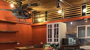 Una cocina con una isla de ladrillo, taburetes de madera, un microondas y un modelo de helicóptero.