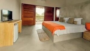 A bedroom with a bed, a TV, a desk, and a balcony.