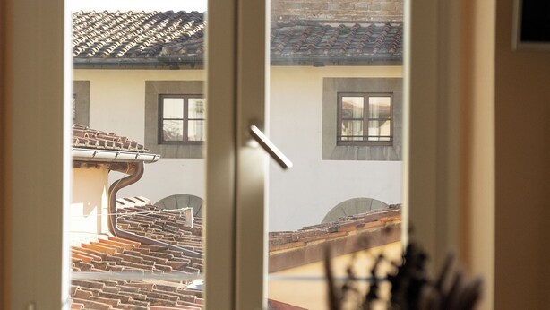 A view through a window of a building with a tiled roof and a brick wall. - Strozzi Apartment with view (Firenze)