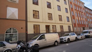 A row of parked cars in front of a building with multiple windows and a door. - Spacious apartment5 min from the center (Stockholms)
