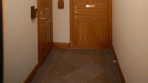 A hallway with two wooden doors, a light fixture, and a tiled floor. - Spacious apartment5 min from the center (Stockholms)