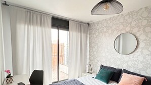 Et moderne soveværelse med en stor seng, et skrivebord og en stol.