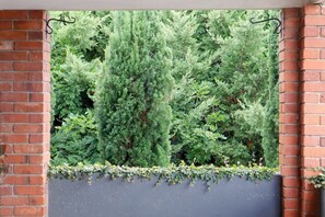 A view through a brick archway with dense green foliage.