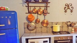 Una cocina compacta con un refrigerador azul, lavadora, horno y estufa.