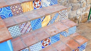 Una escalera con baldosas de colores y diseños variados que conduce a una pared verde y una pared de piedra.