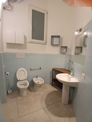 A bathroom with a toilet, bidet, sink, and mirror. - Le Casette di Laura: studio apartment 1 (Palermo)