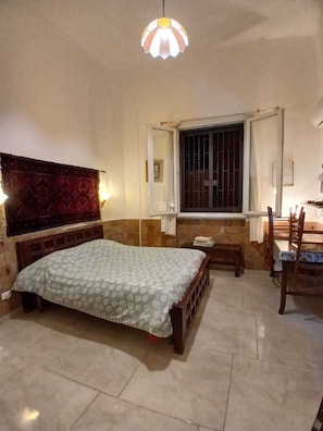 A bedroom with a bed, a window with bars, a bedside table, and a chair. - Le Casette di Laura: studio apartment 1 (Palermo)