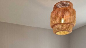 Un dormitorio con cama, mesita de noche con lámpara, lámpara colgante y un cuadro en la pared.