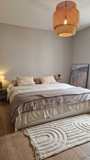 A bedroom with a bed, a bedside table with a lamp, a hanging light fixture, and a painting on the wall. - Meu Sonho: um Alojamento familiar próximo da praia com terraço e ar-condicionado (Alcabideche)