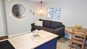 A modern living room with a dark brown sofa, a round mirror, and a wooden dining table with chairs. - Meu Sonho: um Alojamento familiar próximo da praia com terraço e ar-condicionado (Alcabideche)