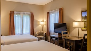Une chambre d’hôtel avec deux lits, un bureau doté d’un téléviseur à écran plat, une chaise et deux lampes.