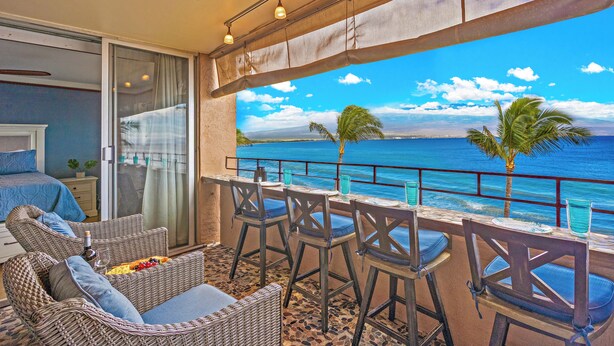 Un balcone con mobili in vimini, un tavolo e sedie, e vista sull'oceano.