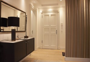 A hallway with a dark-colored console table, a mirror, and a white door. - Seestern Vacation Rental with Beach Chair & Pool | Terrace | Family (Binz)