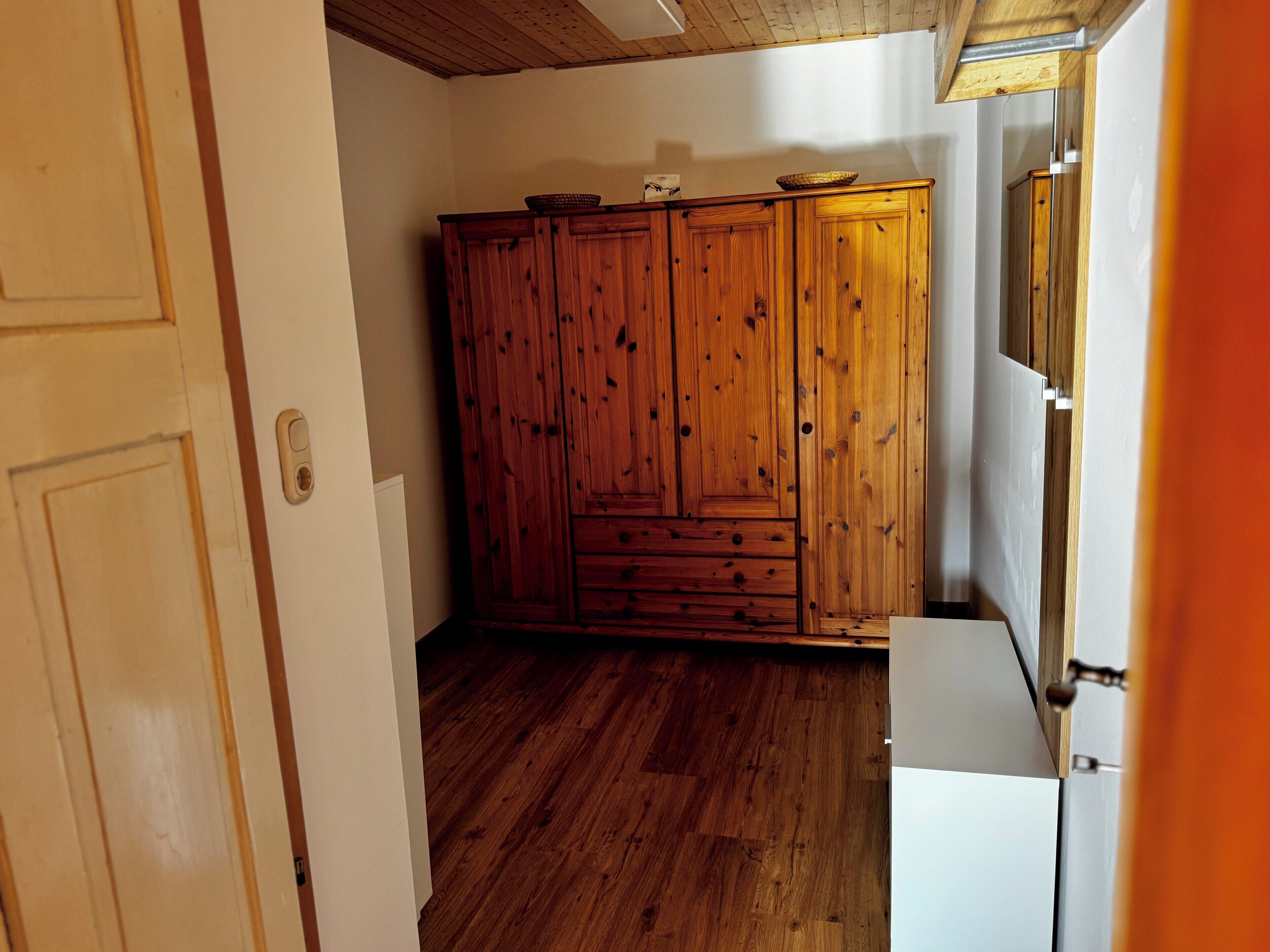 A room with wooden cabinets, a white door, and a wooden floor.