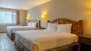 Une chambre d’hôtel avec deux lits, des têtes de lit en bois, des lampes de chevet et une fenêtre avec des rideaux.
