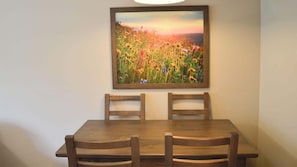 Ein Essbereich mit einem Holztisch und zwei Stühlen, darüber an der Wand ein gerahmtes Gemälde eines Blumenfeldes.