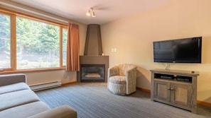 A living room with a fireplace, a television, and a sofa. - Cahilty #241/243 1 Bedroom Hotel Room (Sun Peaks)