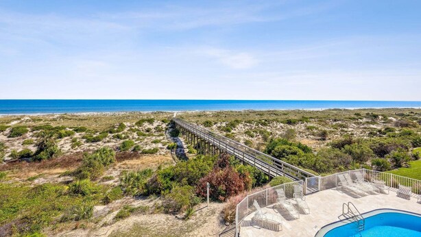 Vista sulla spiaggia con una passerella in legno e una zona piscina.