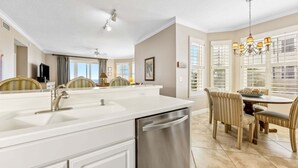 Una cucina moderna con un'isola grande, elettrodomestici in acciaio inossidabile e una zona pranzo con sedie a righe.