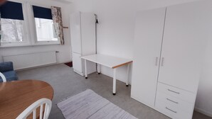 A room with a wooden table, white chairs, a white desk, and a wardrobe. - Svenshögens vandrarhem (Svenshögen)
