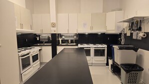 A modern kitchen with white cabinets, black countertops, and white appliances. - Svenshögens vandrarhem (Svenshögen)