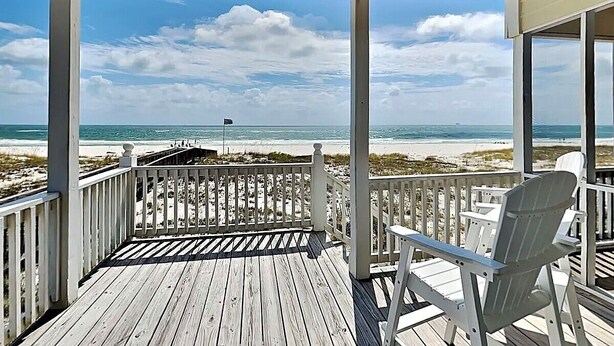Eine Holzterrasse mit Blick auf Strand und Meer.