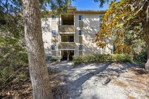 A multi-story building with a central entrance, surrounded by trees and shrubs. - 4f Amelia Landings 2 Bedroom Condo (Fernandina Beach)