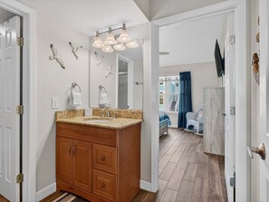 Un bagno con un mobile bagno in legno, uno specchio grande e una lampada a sospensione.