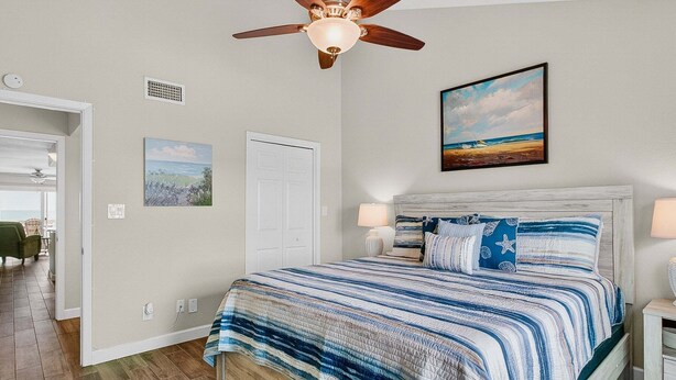 A bedroom with a bed, ceiling fan, artwork, and a view of the outdoors. - Kontiki Bayfront K304 3 Bedroom Condo (Rockport)
