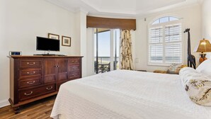 Une chambre à coucher avec un grand lit, une commode, un téléviseur et une fenêtre avec des volets.