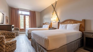 A hotel room with two beds, a wooden headboard, a nightstand, a desk, a chair, and a window with curtains.