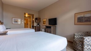 Quarto de hotel com duas camas, televisão, máquina de café e um quadro na parede.