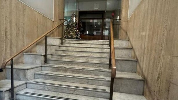Un escalier en marbre avec des rampes métalliques menant à une entrée.