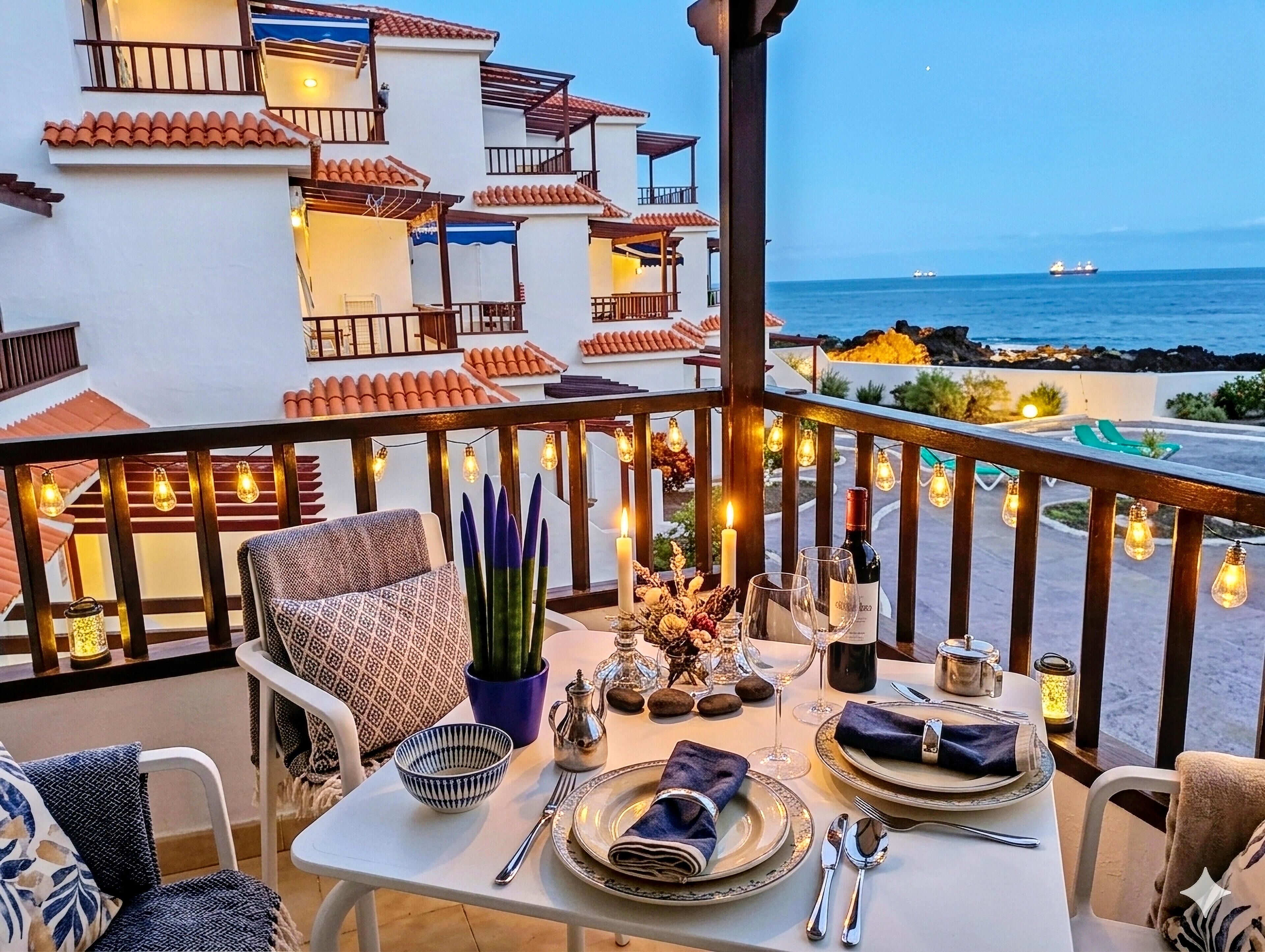 Un comedor con una mesa dispuesta para dos personas, con vistas a la costa, edificios y un barco a lo lejos.