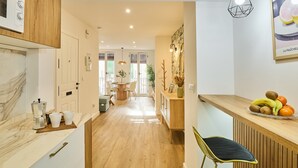 A modern kitchen with a coffee machine, a dining area with a table and chairs, and a fruit bowl on the counter. - El Mirador de Neptuno: Your Private Balcony Over Priego de Córdoba’s History (Priego de Córdoba)