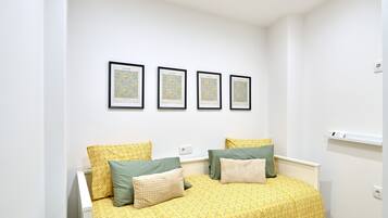 Une chambre à coucher avec un lit double, deux tables de chevet, un mur blanc et quatre tableaux encadrés.