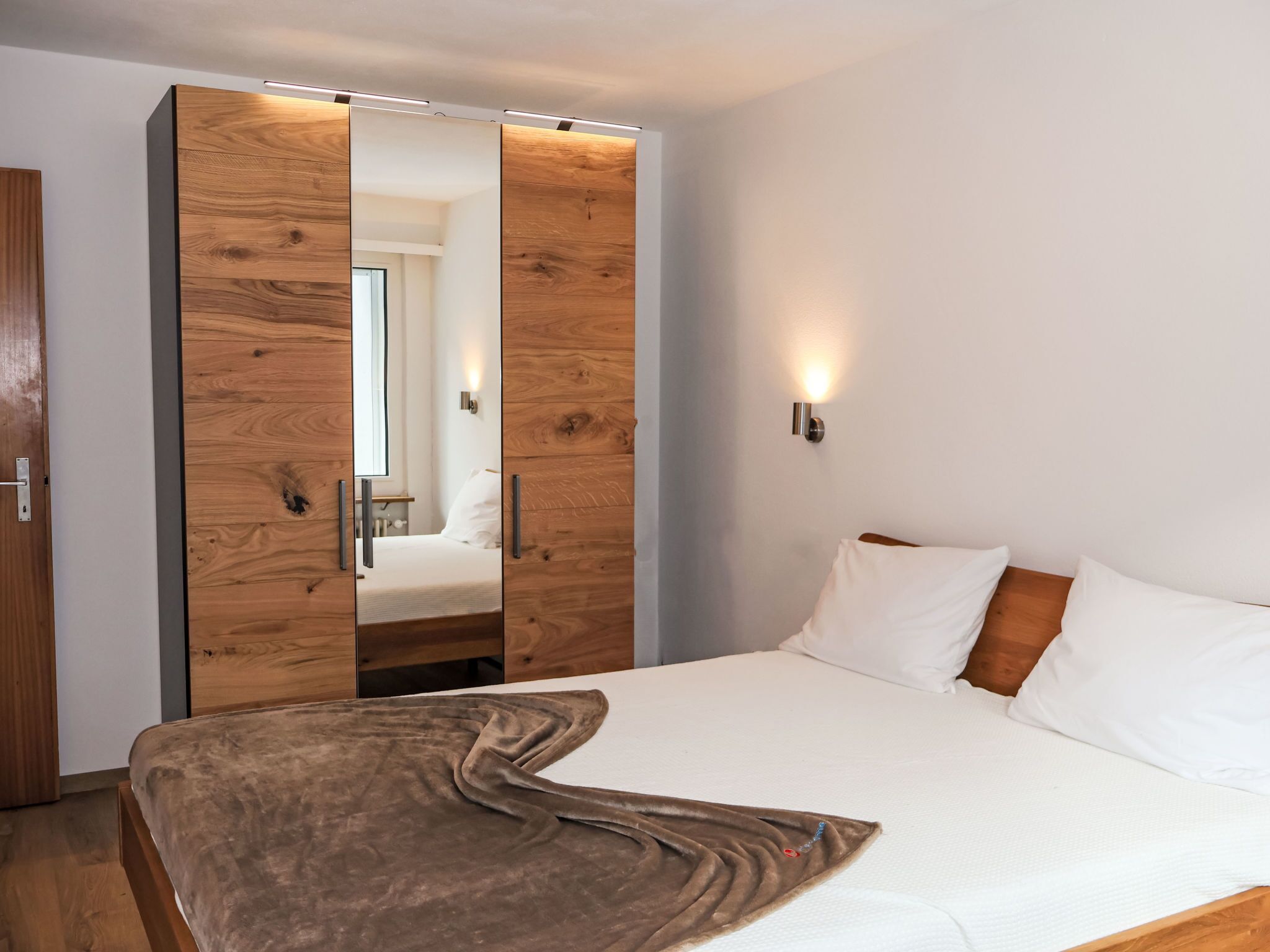 Une chambre à coucher avec un lit, une armoire en bois et un miroir.