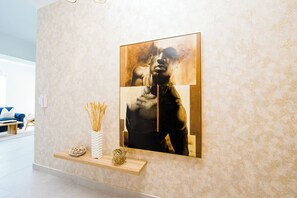 A modern living room with a large abstract painting on the wall, a wooden shelf with decorative items, and a patterned wallpaper. - Cozy 1-bedroom apartment in nice Santo Domingo with AC (Santo Domingo)