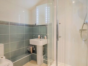 Ein modernes Badezimmer mit Duschkabine aus Glas, einem Standwaschbecken und einer Toilette.
