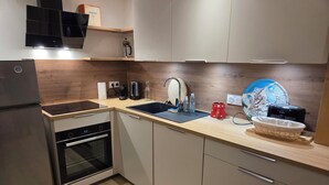 Una cocina moderna con horno empotrado, lavabo y cafetera.