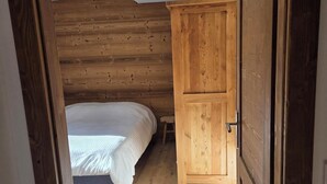 Un dormitorio con un armario de madera, una cama y suelo de madera.