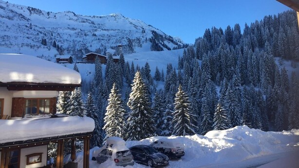 A snow-covered mountain landscape with a building and parked cars. - House Annabelle Top 1 (Damüls)