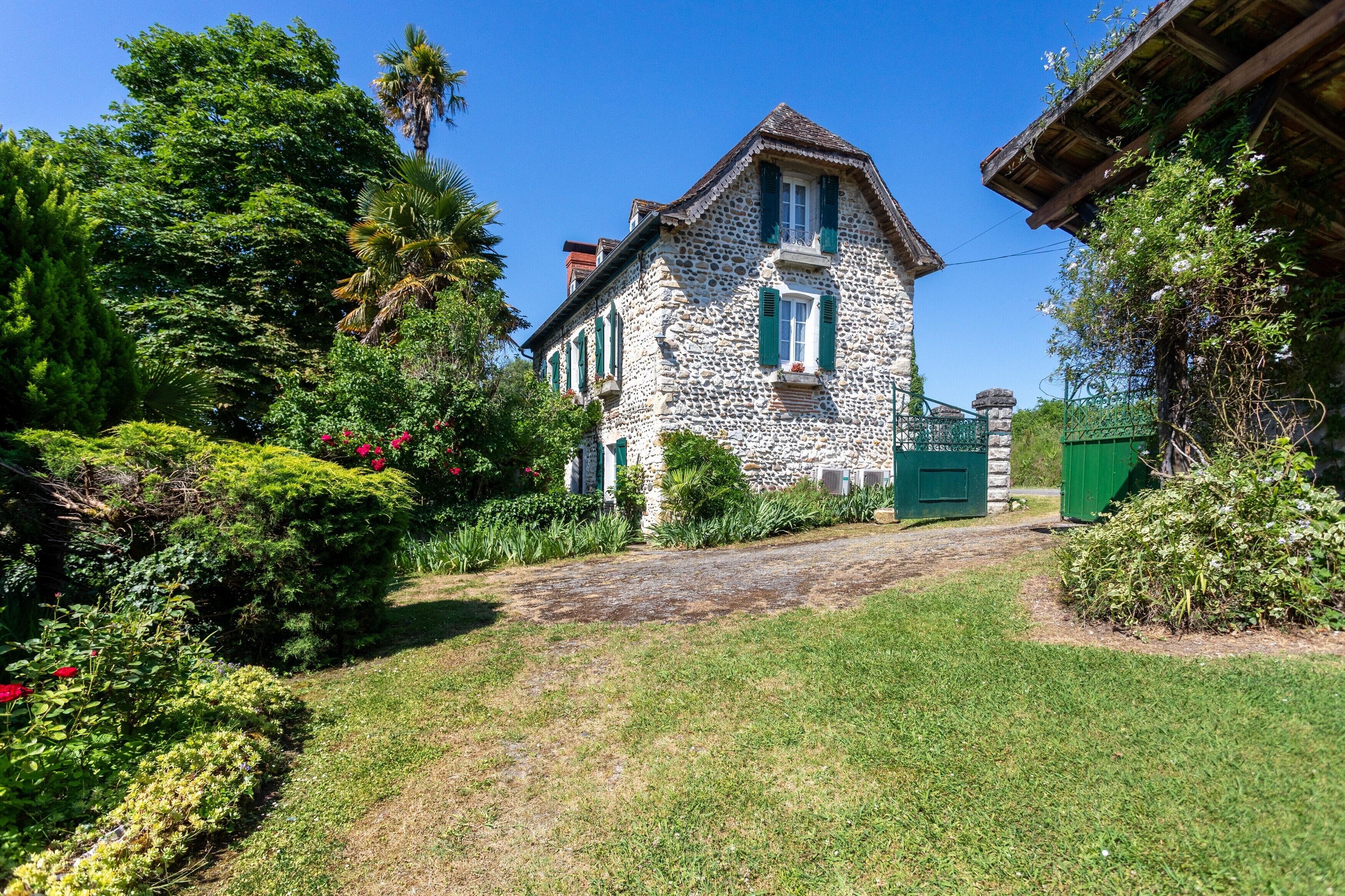 Une maison en pierre avec un jardin et un chemin qui y mène.