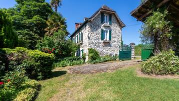 Une maison en pierre avec un jardin et un chemin qui y mène.