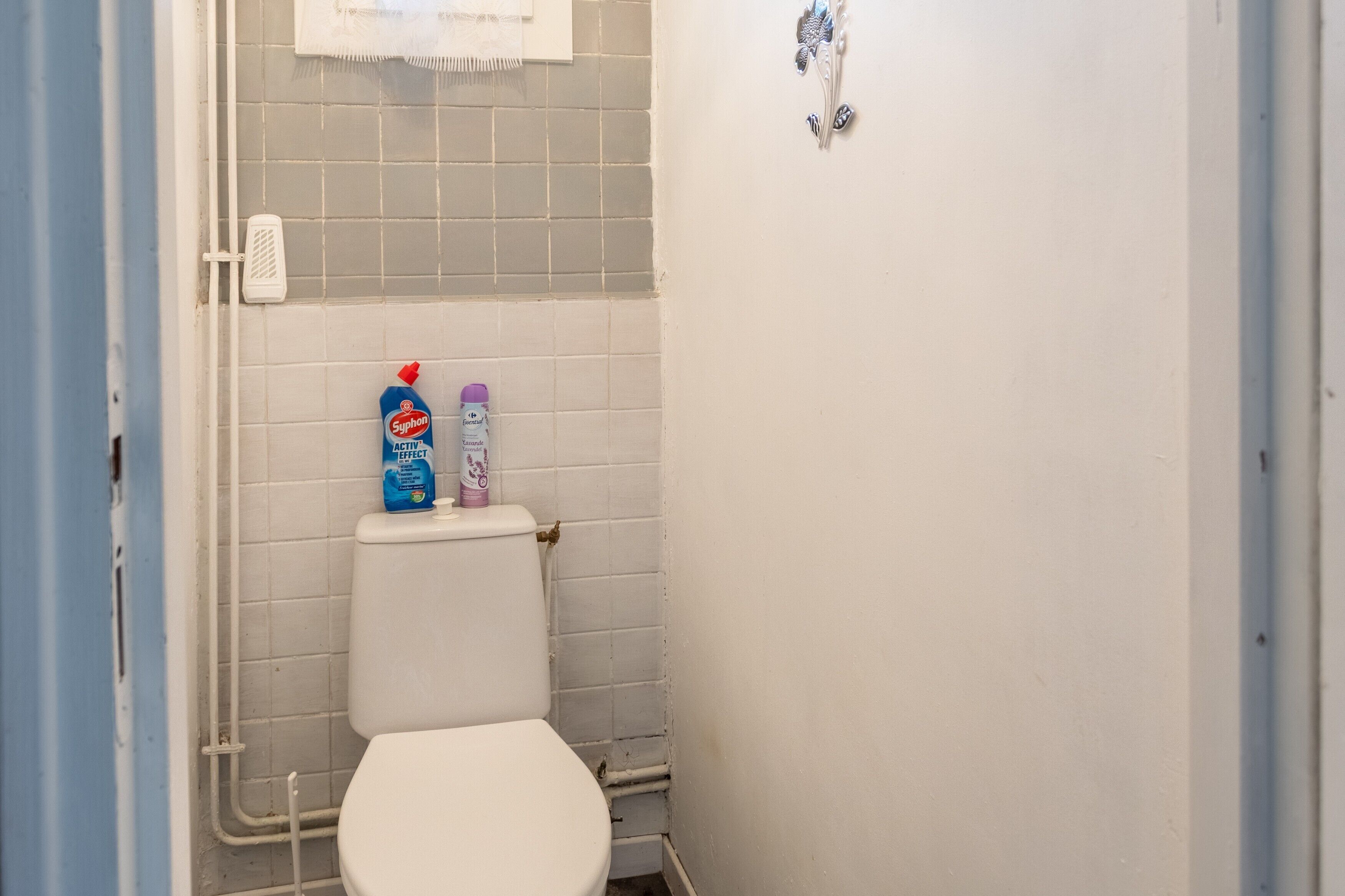 Ein kleines Badezimmer mit Toilette, Dusche und zwei Kosmetikflaschen an der Wand.