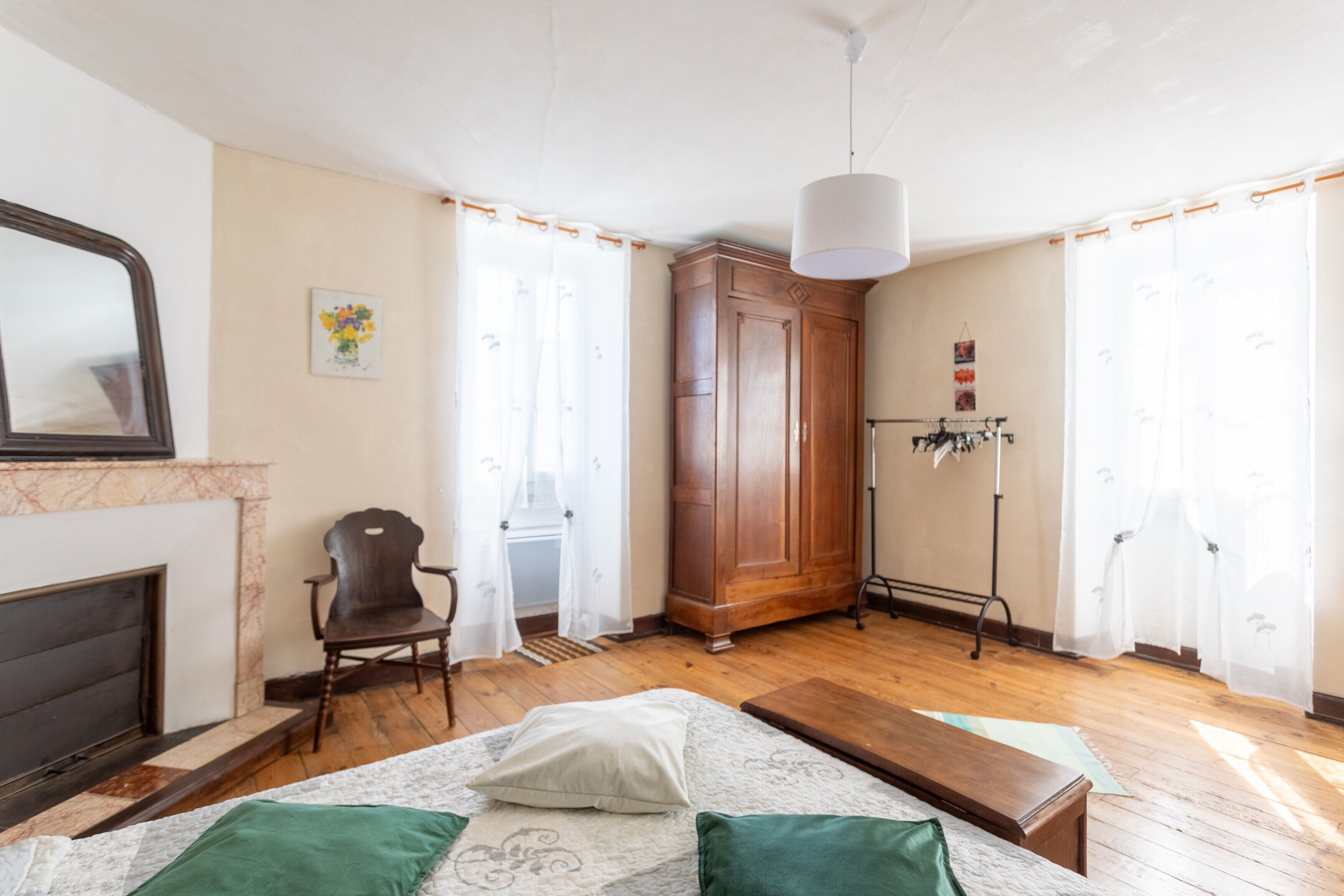 A bedroom with a bed, a chair, a wardrobe, a radiator, and a fireplace.
