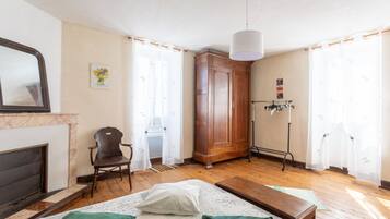 A bedroom with a bed, a chair, a wardrobe, a radiator, and a fireplace.