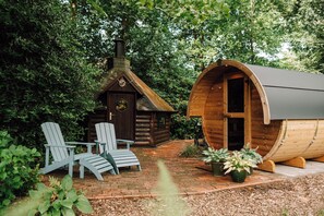A wooden cabin with a chimney, a log cabin, and a wooden barrel house. There are two Adirondack chairs outside. - Cozy vacation homes and apartments - here you will find peace and relaxation (Emstek)