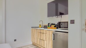 Una cocina compacta con microondas integrado, cafetera y un refrigerador pequeño.