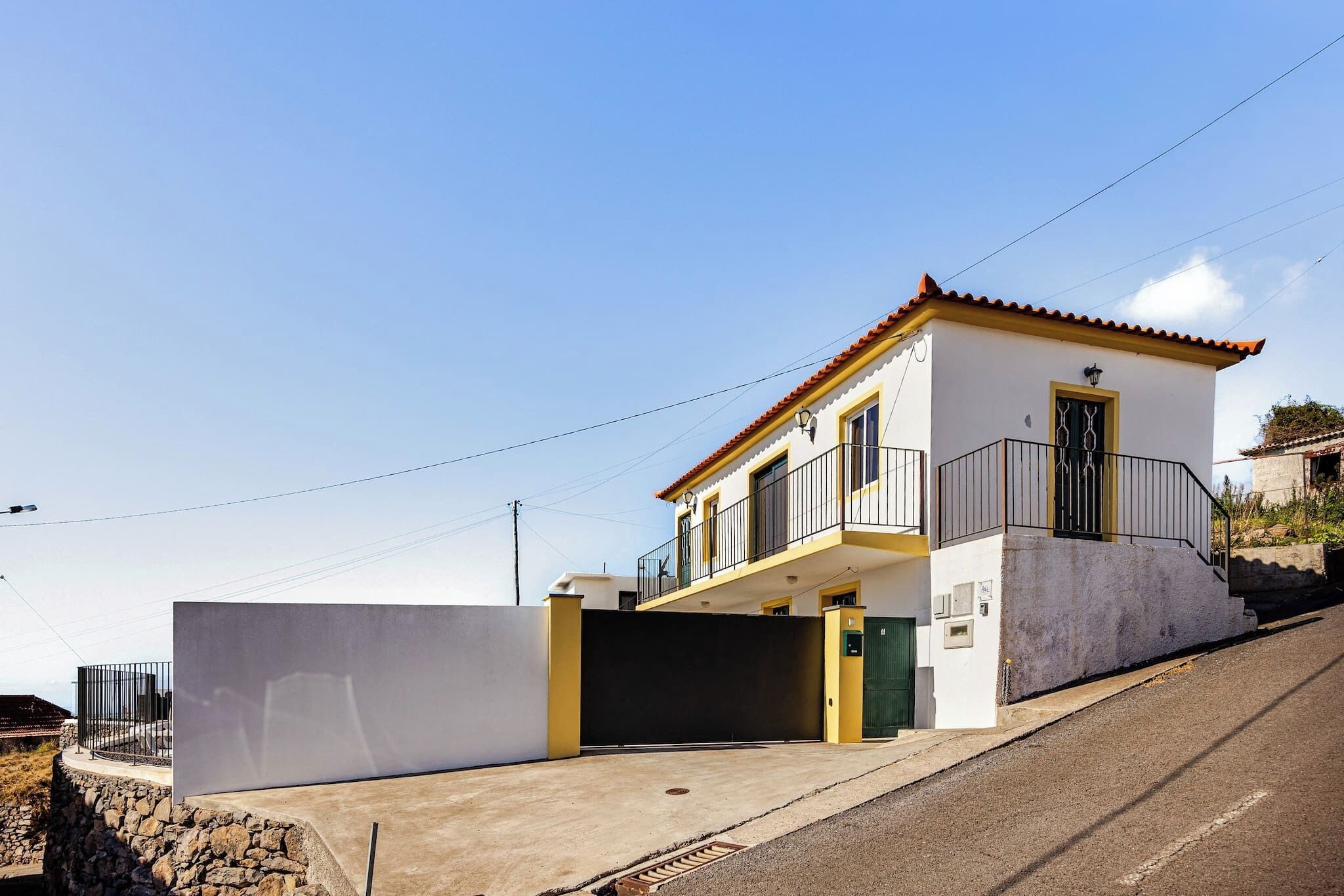 A two-story house with a balcony, a garage, and a stone wall.